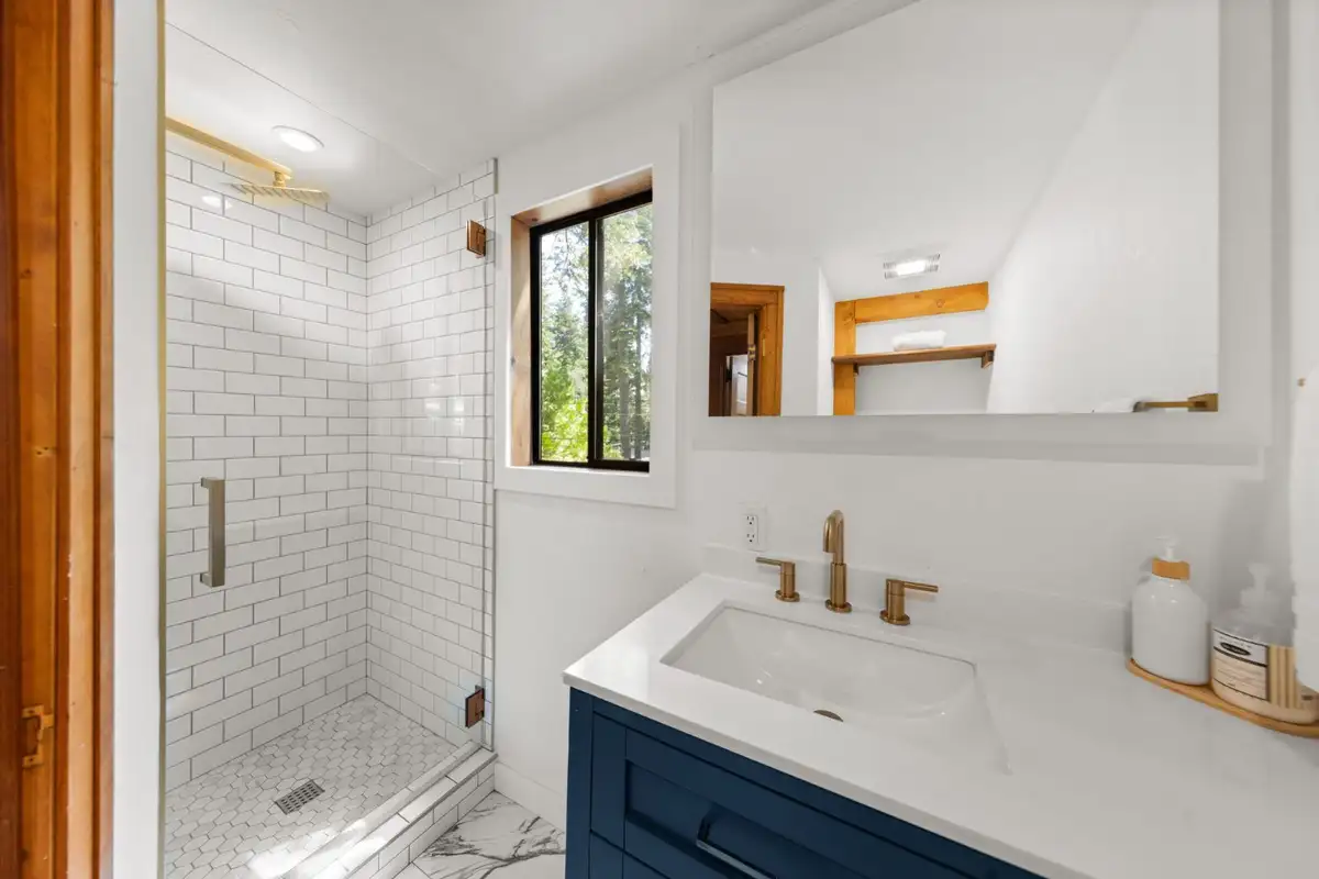 Bathroom with a white subway-tile shower and blue vanity, Homewood Cabin in the Pines
