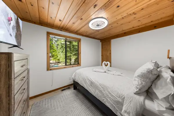 Bedroom with a bed, dresser and pine ceiling, Homewood Cabin in the Pines