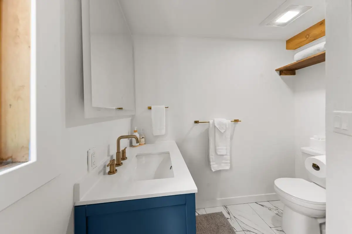 Bathroom with a blue vanity and marble-look floor, Homewood Cabin in the Pines