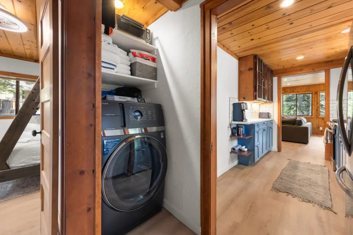 Front-load washer closet beside a hallway to the kitchen, Homewood Cabin in the Pines