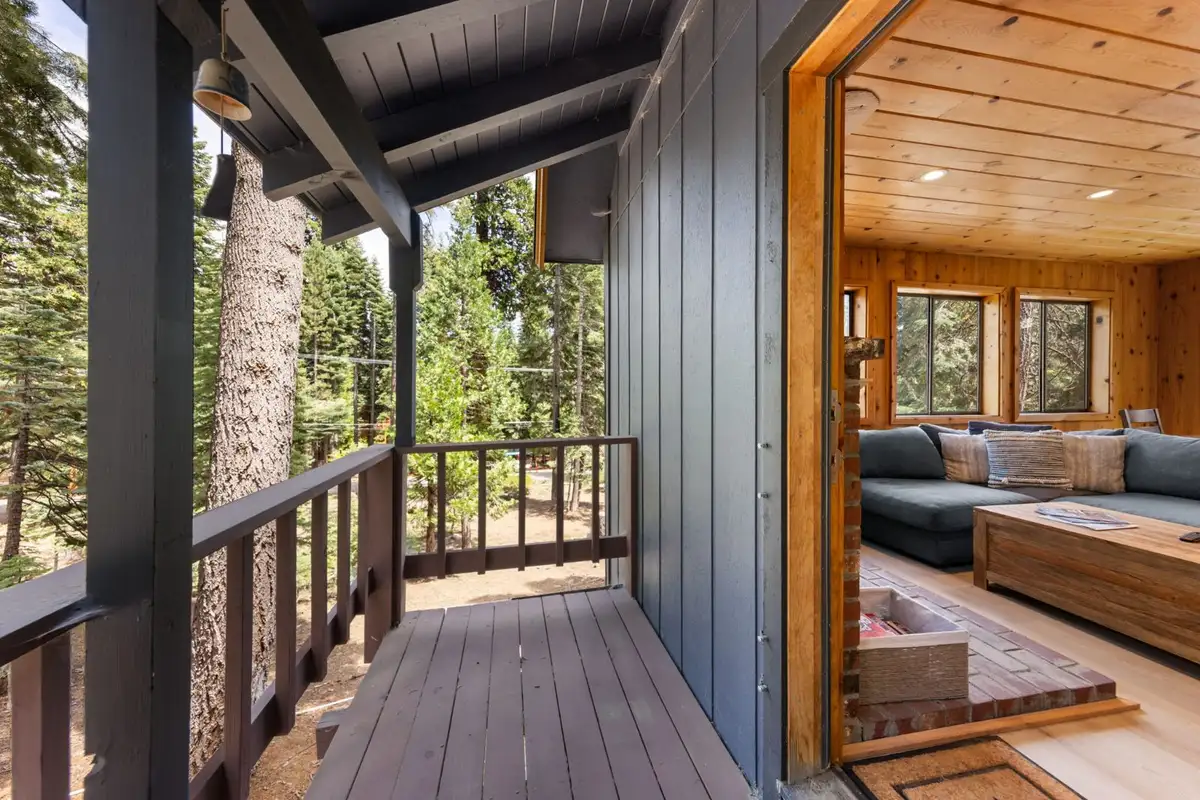 Covered balcony beside an open door to the living room, Homewood Cabin in the Pines