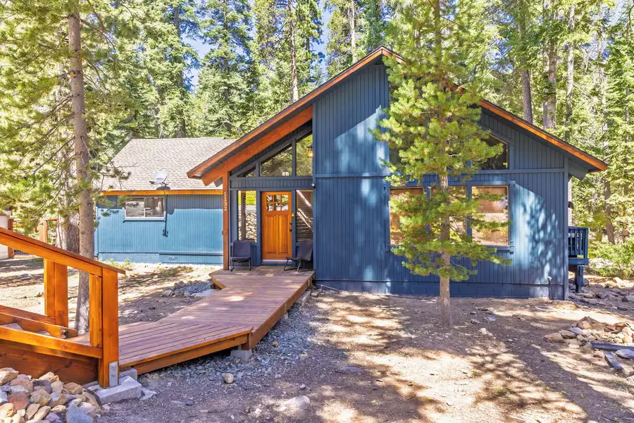 Dark blue A-frame cabin among pines with a wooden deck, Grand Regency Retreat