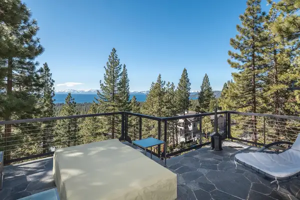 Stone patio with lounge seating and Lake Tahoe visible beyond the pines, Skylake Serenity Retreat