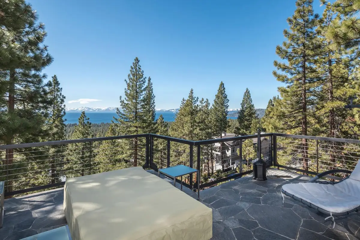 Stone patio with lounge seating and Lake Tahoe visible beyond the pines, Skylake Serenity Retreat