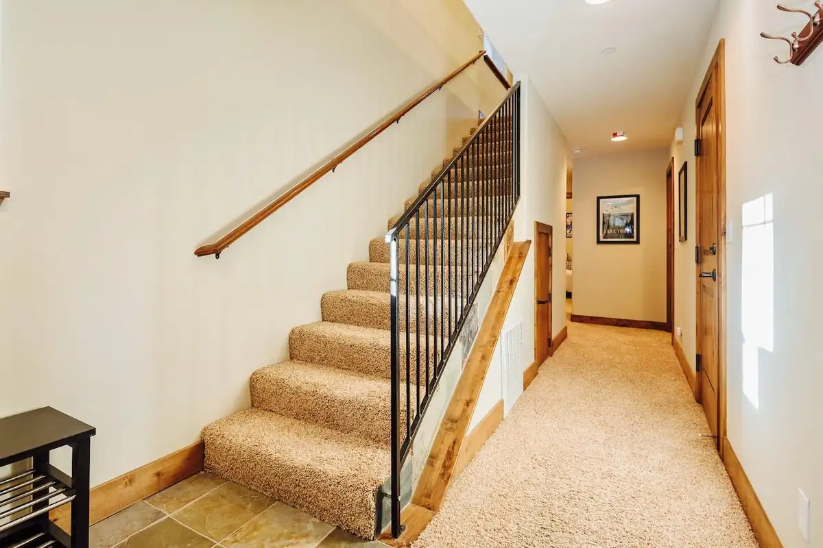 Carpeted staircase with iron railing beside a hallway, Trout and About