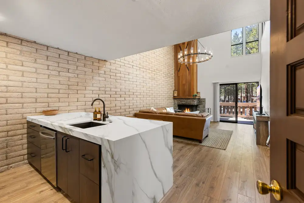 Marble waterfall kitchen island with brick accent wall and cozy fireplace, Treetop on Country Club, an MG home in Incline Village