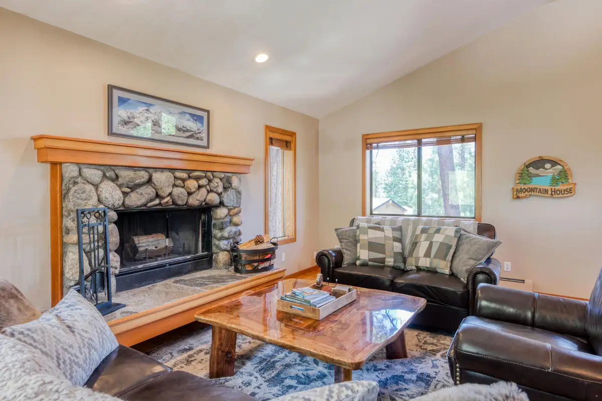 Living room with stone fireplace and leather sofas, Lunar Lakeview Haven
