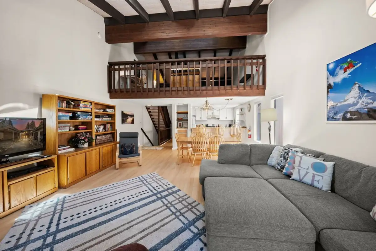 Living room with sectional, bookshelves and loft above, Skiway Suite