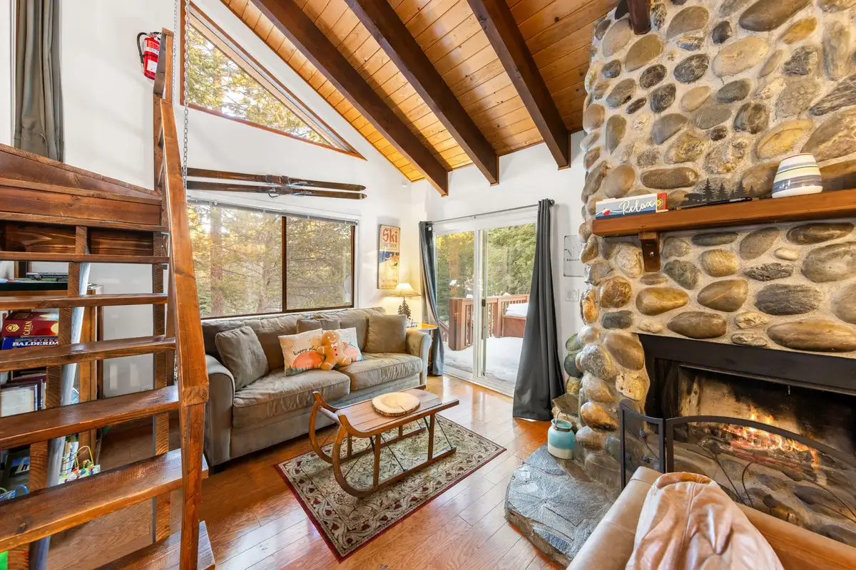 Living room with river-rock fireplace and ladder to loft, Sierra Woodlands Getaway