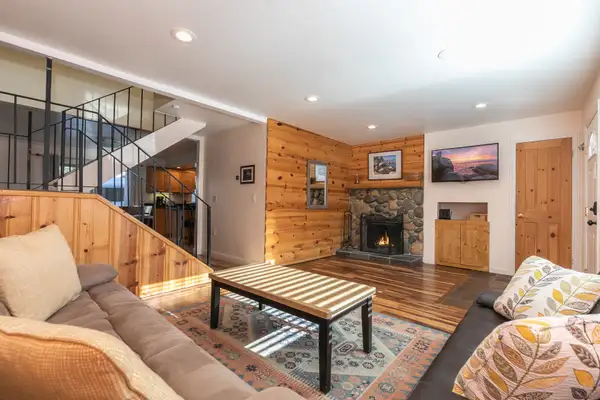Living room with stone fireplace and wood-paneled wall, Trailside Tahoe Townhouse