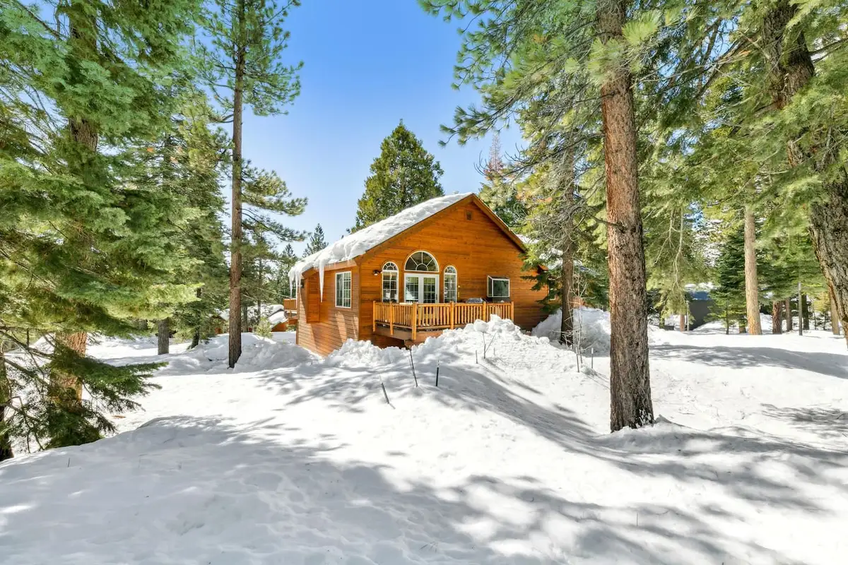 Wood home with a deck seen across a snowy yard, Hastings Hideaway Cabin