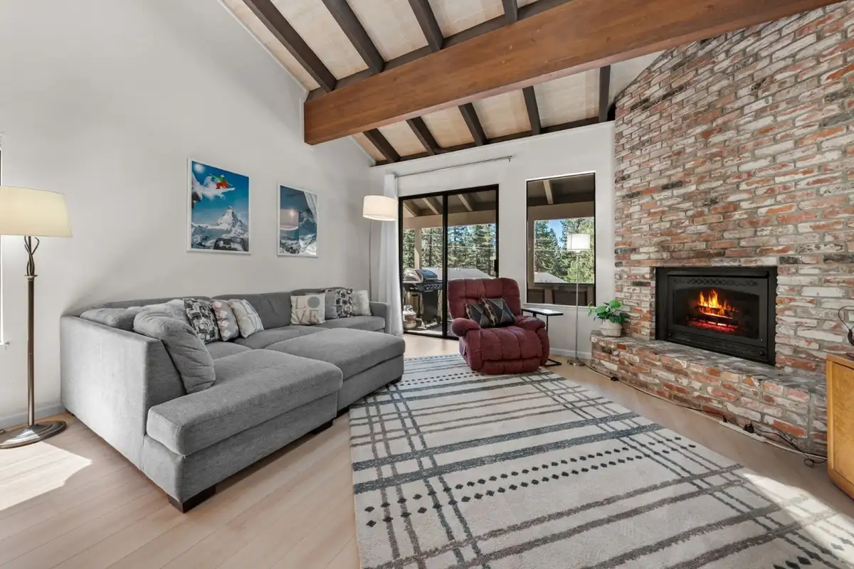 Living room with brick fireplace and gray sectional, Skiway Suite