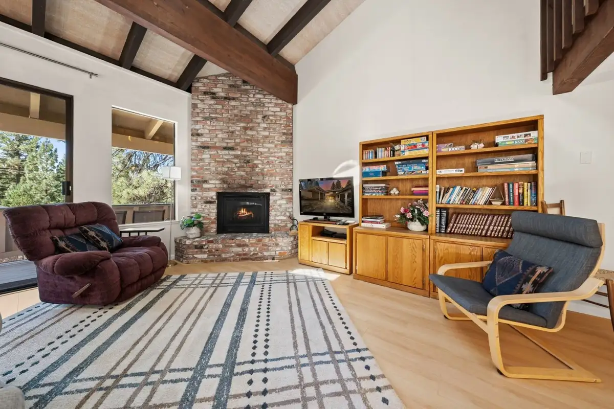 Living room with brick fireplace and bookshelves, Skiway Suite
