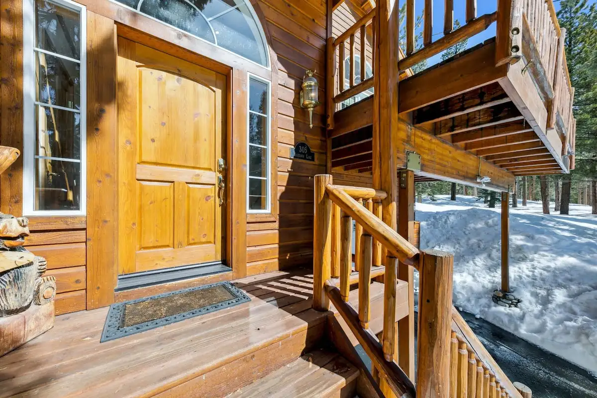 Front door with wood log railings and a snowy yard, Hastings Hideaway Cabin
