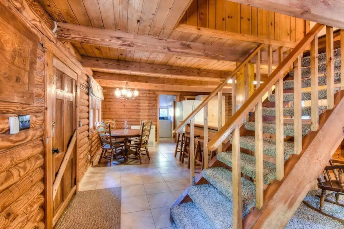Log cabin interior with a staircase and dining table beyond, Enchanted Woods Cabin