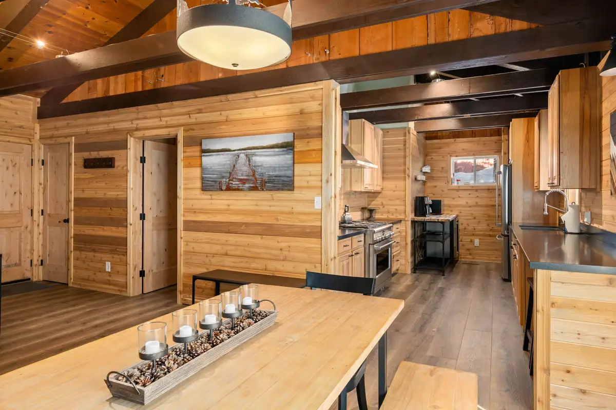 Dining table with wood benches and kitchen beyond, Updated West Shore Cabin 1 mile to Chambers Beach
