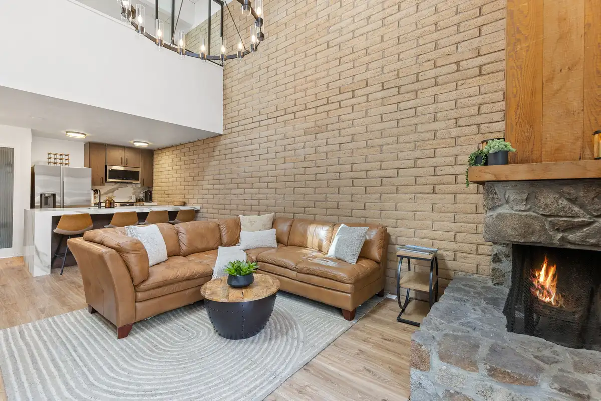 Spacious living room with brick wall, fireplace, and loft overlook above, Treetop on Country Club