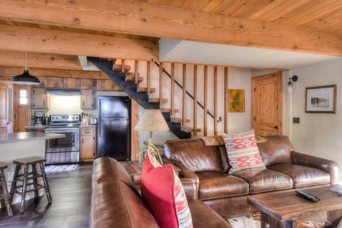Living room with leather sofas, staircase and kitchen beyond, Enchanting Chamberlands Cabin