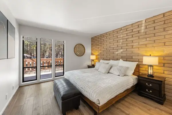 Main-level king bedroom with brick accent wall and forest views, Treetop on Country Club