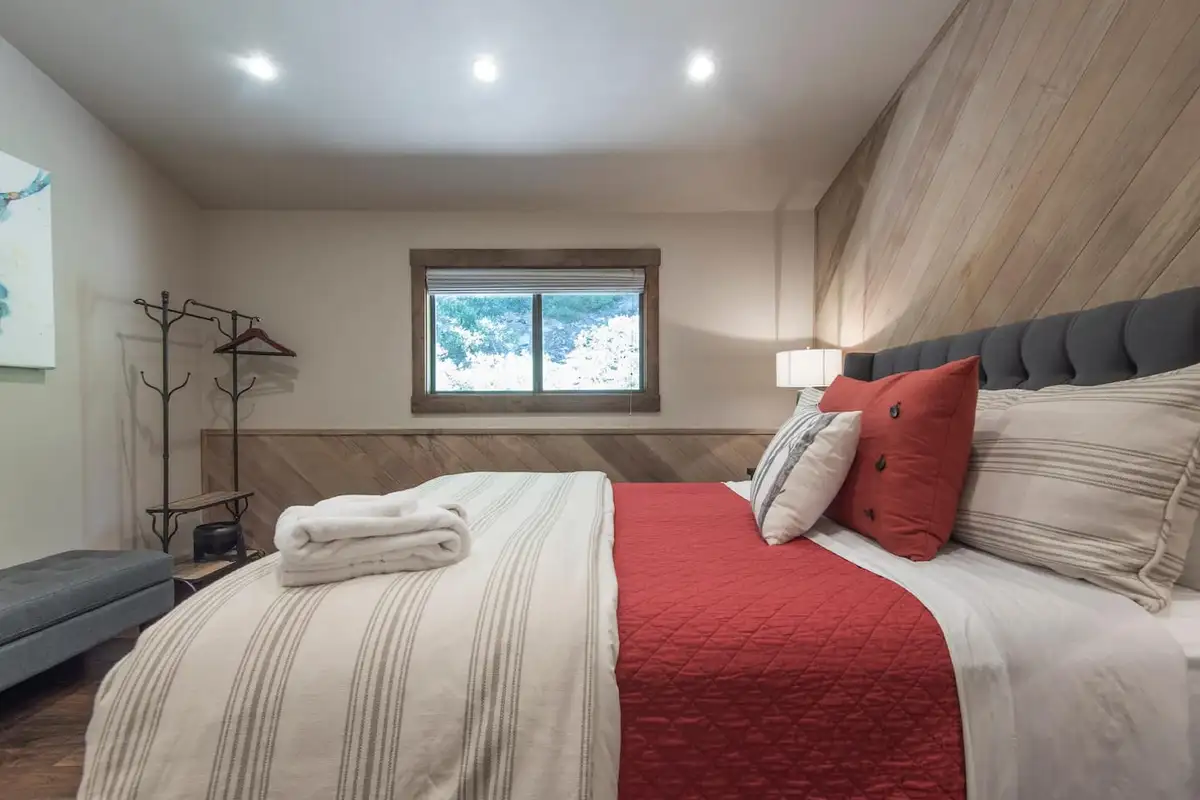 Bedroom with a bed, red quilt and wood-plank wall, Tranquil Tahoe Haven