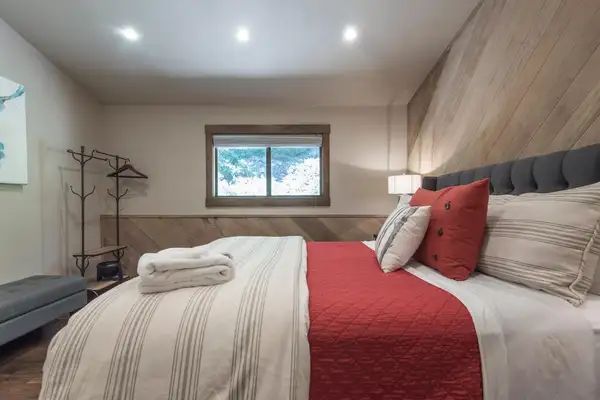 Bedroom with a bed, red quilt and wood-plank wall, Tranquil Tahoe Haven