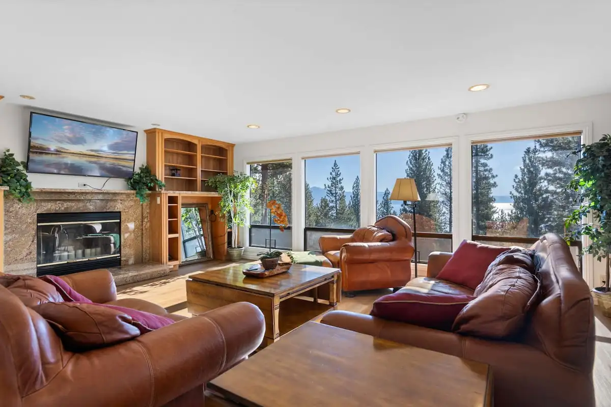 Living room with leather sofas, fireplace and wall of windows, Tranquil Alpine Bliss
