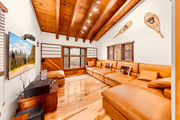 Living room with leather sectional and wood ceiling, Sunlit Incline Retreat