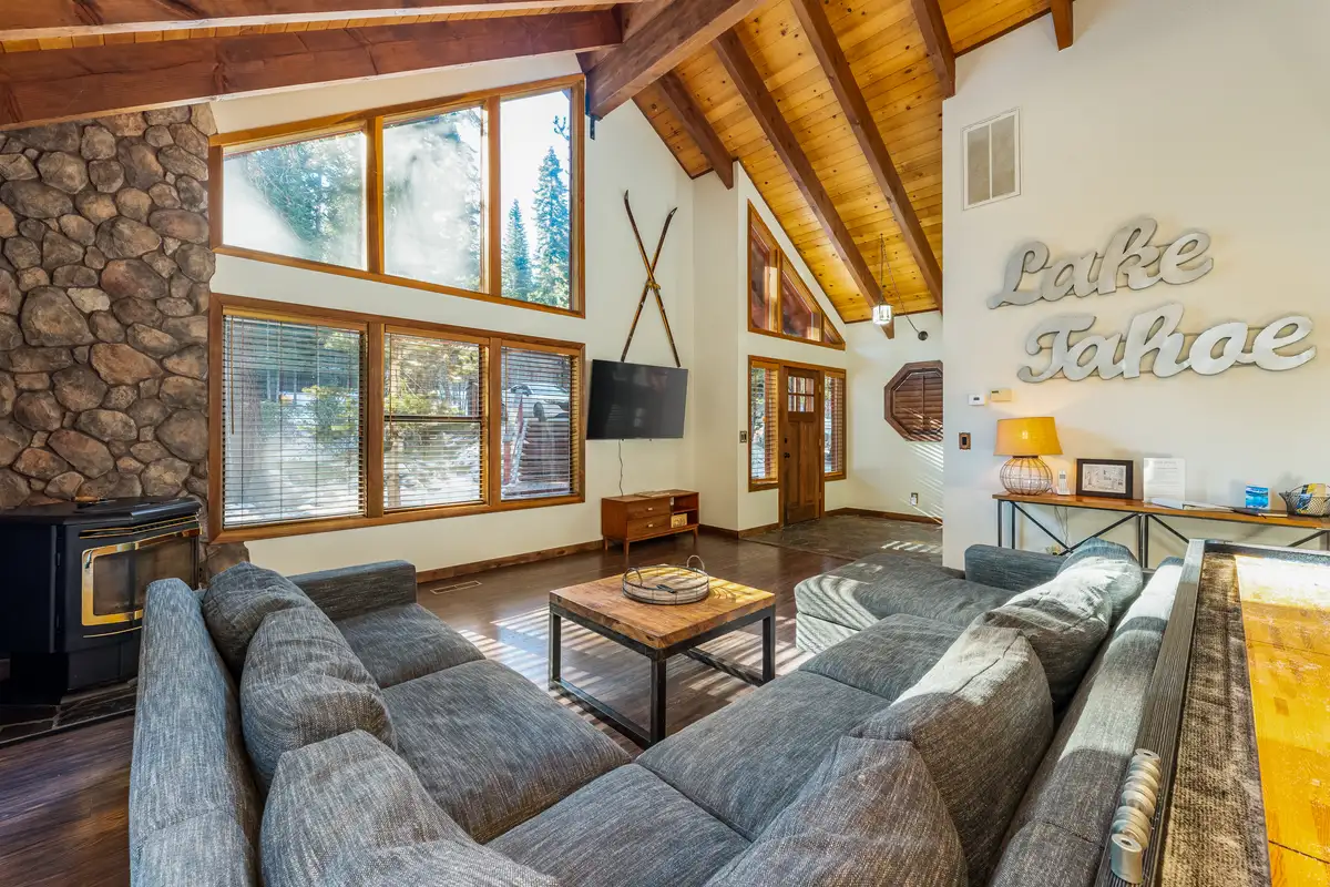 Living room with gray sectional, stone wall and tall windows, Grand Regency Retreat