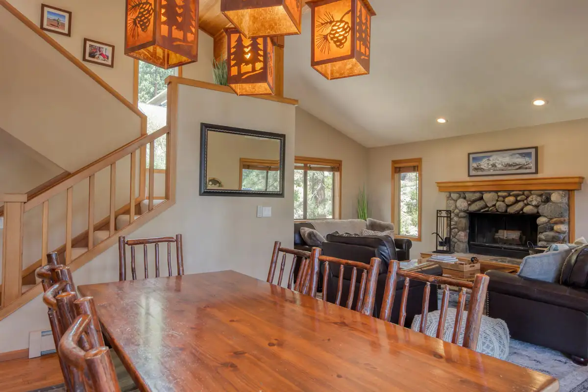 Dining table with rustic chairs near the stairs and fireplace, Lunar Lakeview Haven