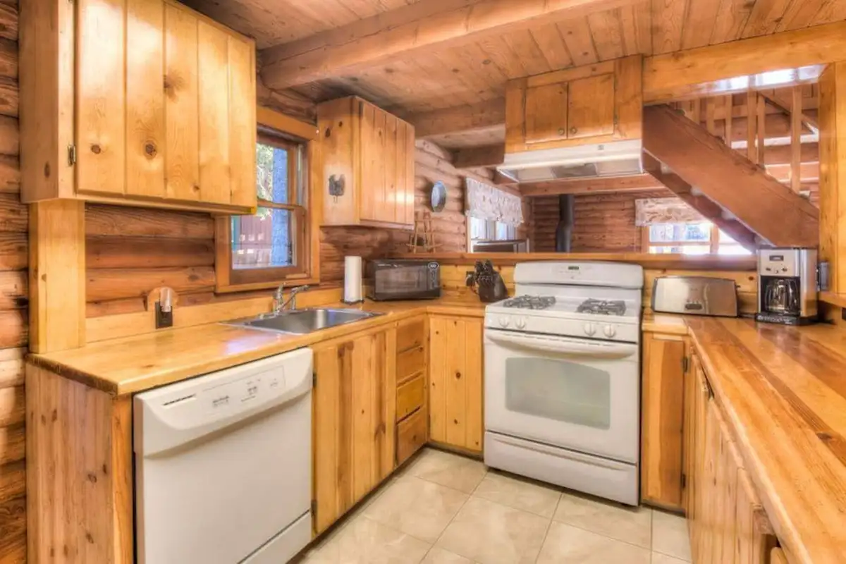 Pine kitchen with a white gas range and dishwasher, Enchanted Woods Cabin