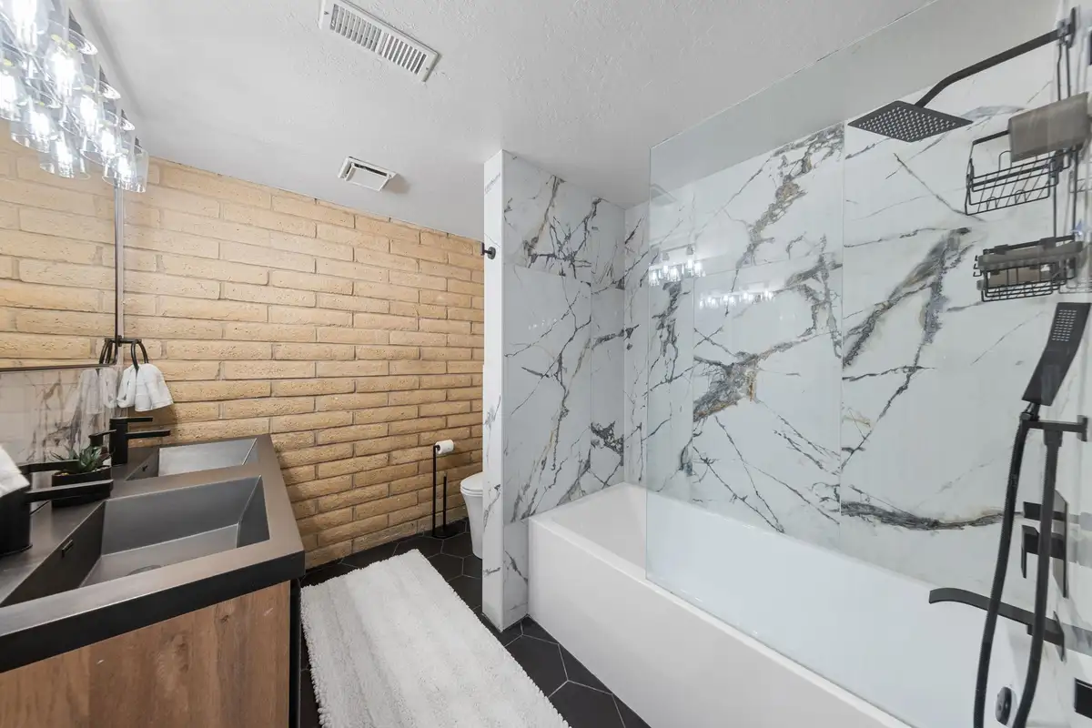 Main bathroom with marble soaking tub, rain showerhead, and brick wall, Treetop on Country Club