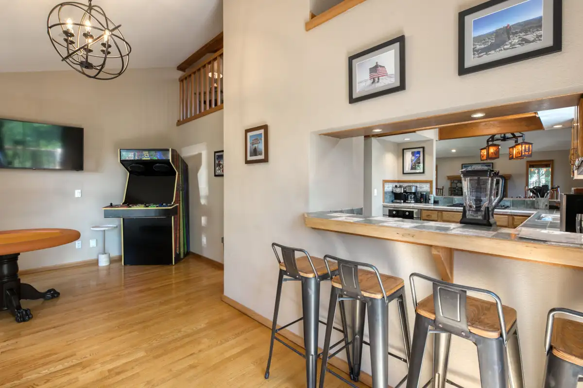 Kitchen bar with metal stools and an arcade machine nearby, Lunar Lakeview Haven