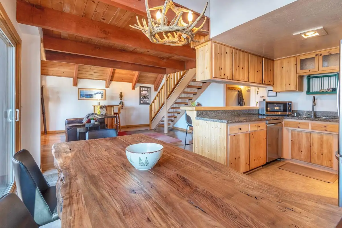 Live-edge dining table with kitchen and stairs beyond, Lakeview Serenity Cottage