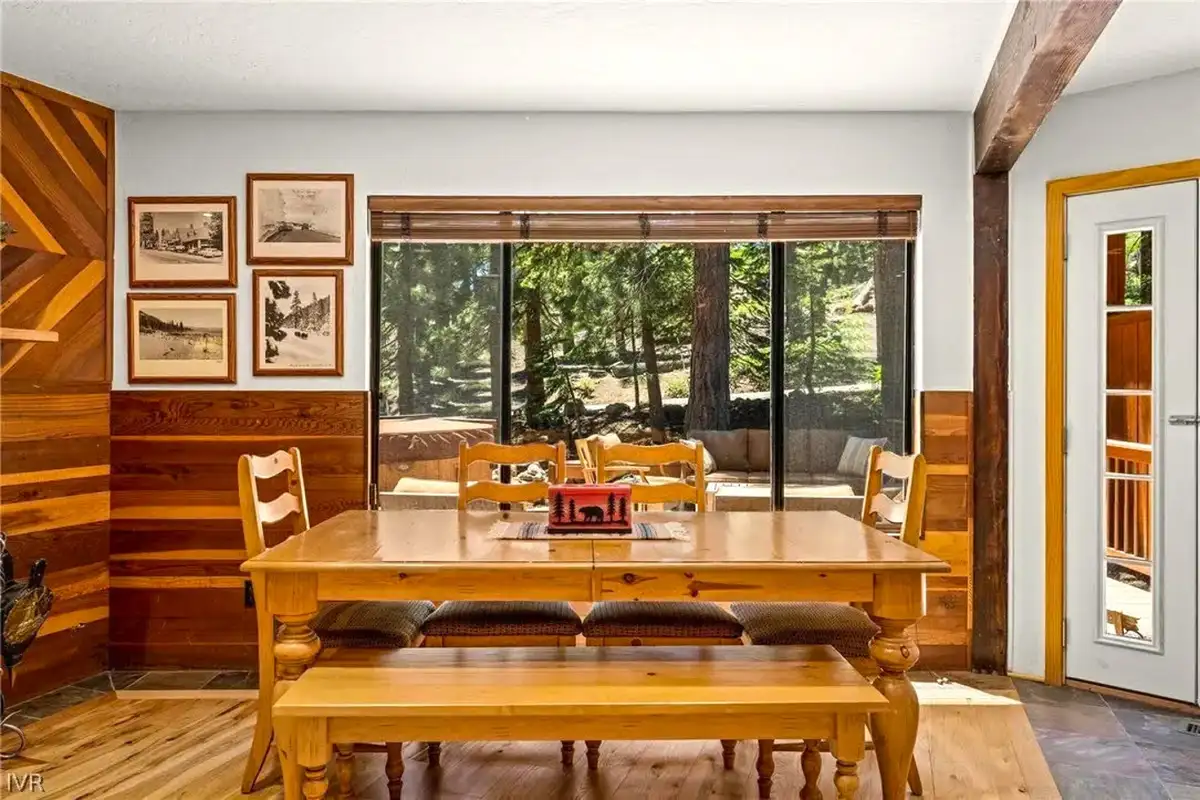 Wood dining table with bench by a large window, Sunlit Incline Retreat