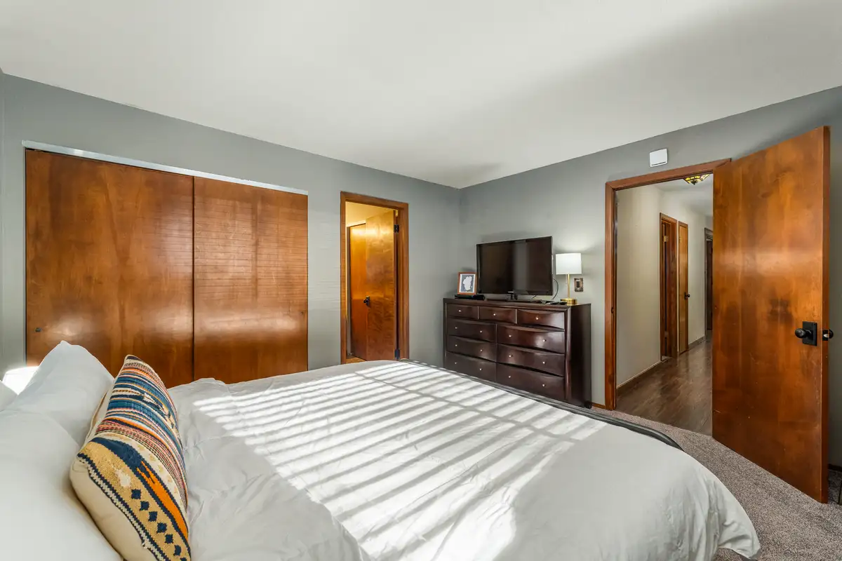 Bedroom with a bed, dresser and wood closet doors, Grand Regency Retreat