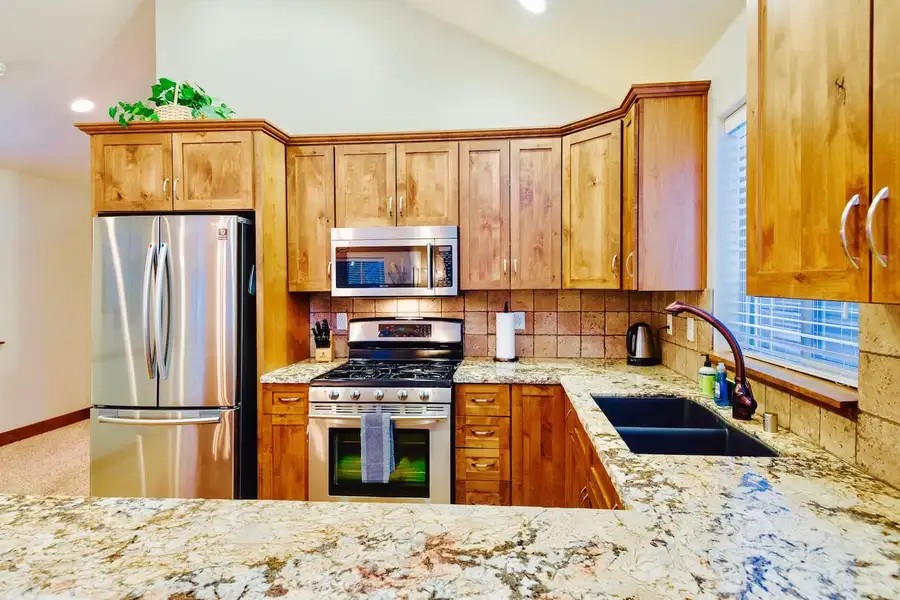 Kitchen with wood cabinets, gas range and granite counters, Trout and About