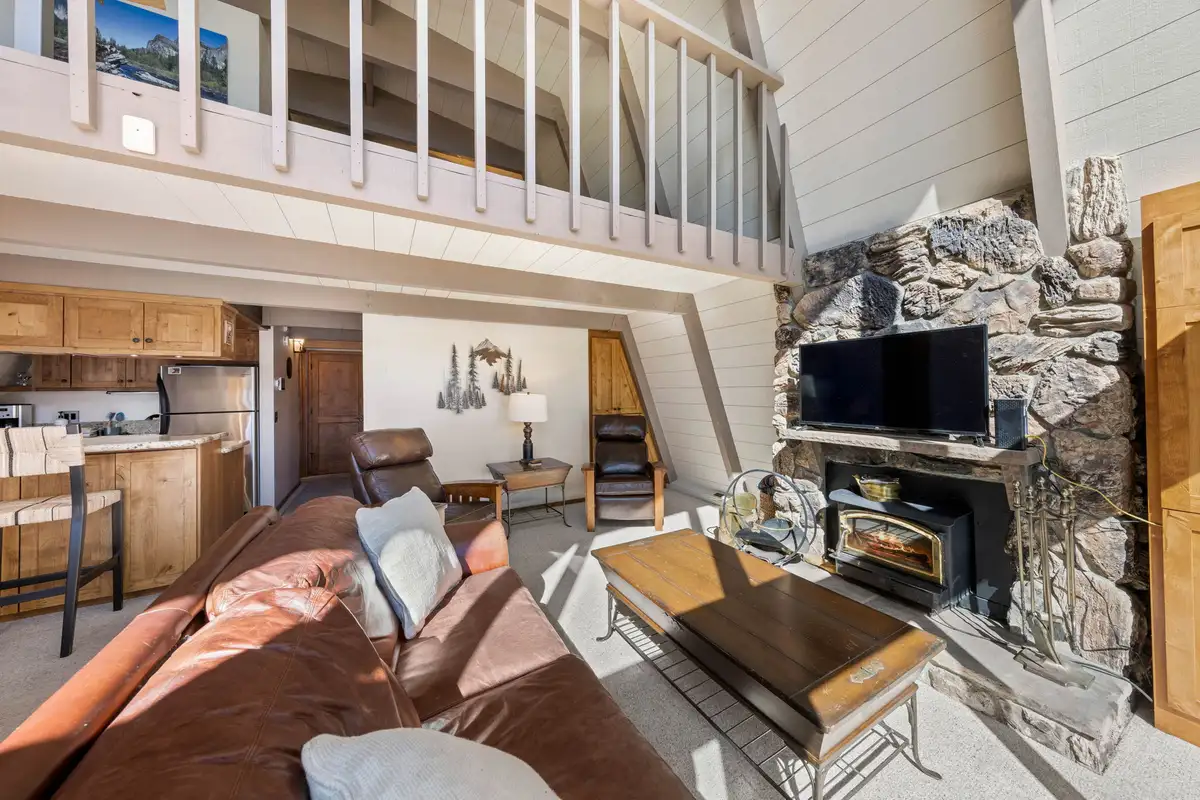 Leather sofa facing a stone fireplace under a loft, Livin' on the Edge