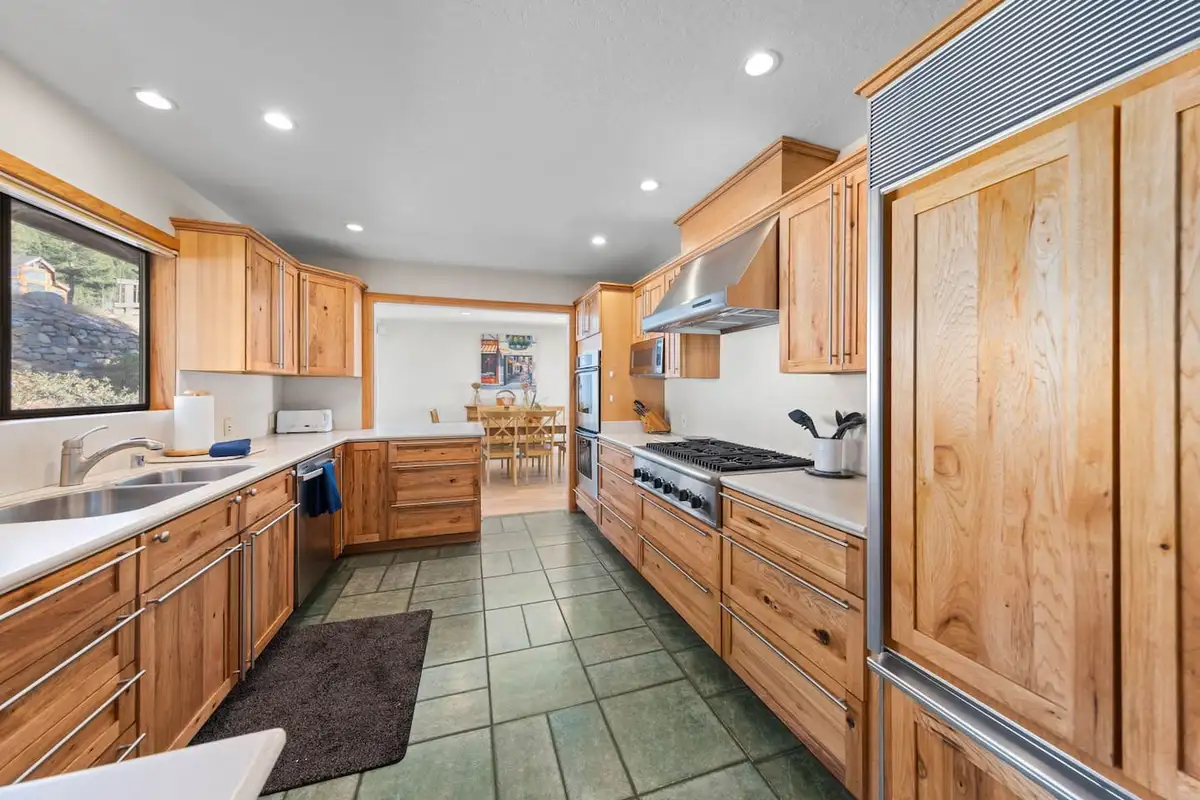 Galley-style kitchen with wood cabinets and stainless range, Tranquil Alpine Bliss
