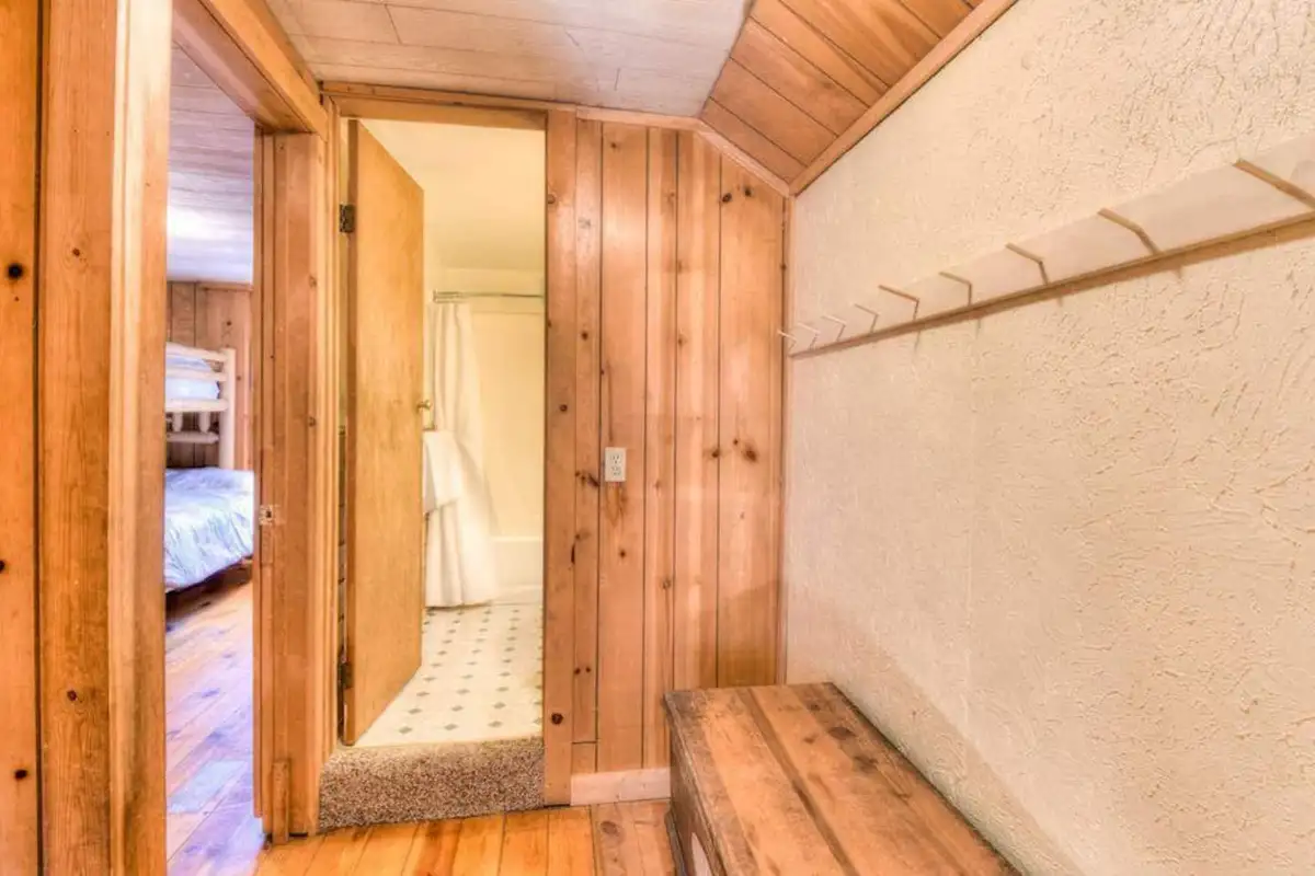 Wood-paneled hallway with coat hooks and a bench, Enchanted Woods Cabin