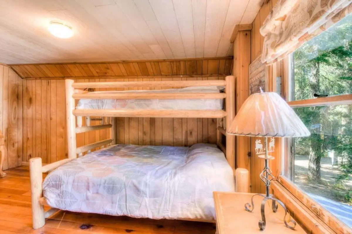 Log-frame bunk bed beside a window, Enchanted Woods Cabin