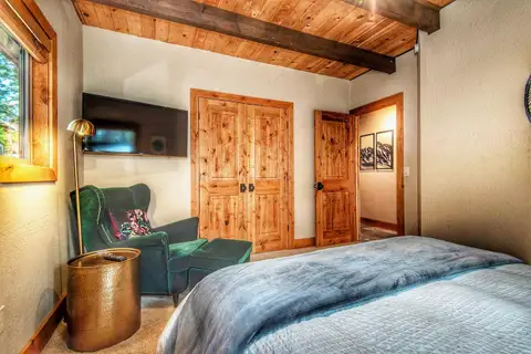 Bedroom with a bed, green armchair and wall-mounted TV, Restful North Ridge