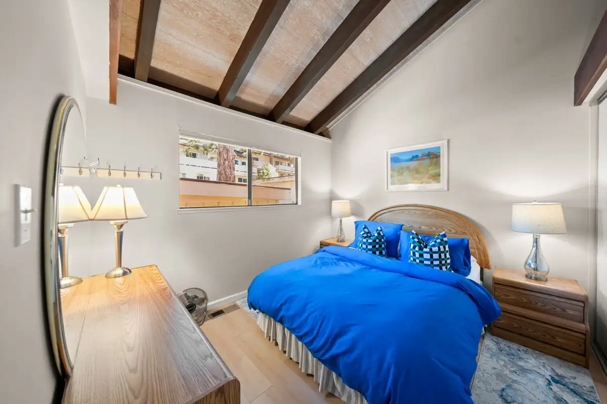 Bedroom with a blue-covered bed and wood beam ceiling, Skiway Suite