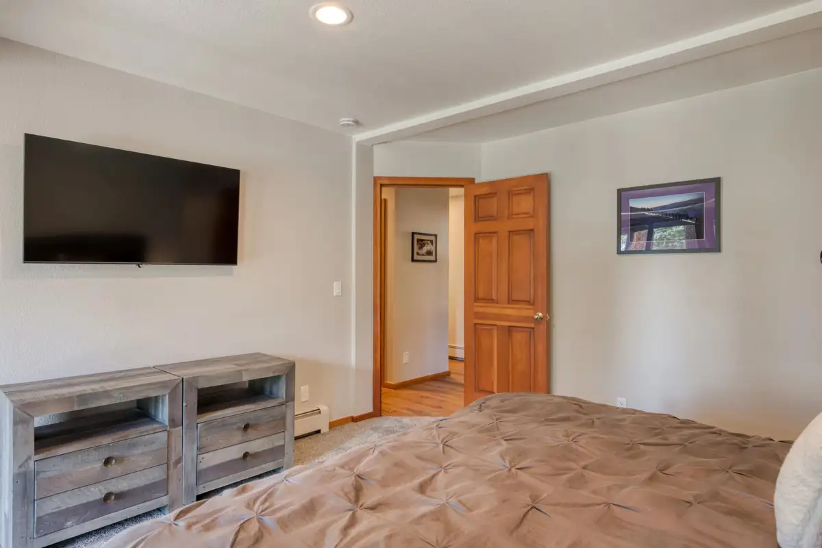 Bedroom with a wall-mounted TV and gray dresser, Lunar Lakeview Haven