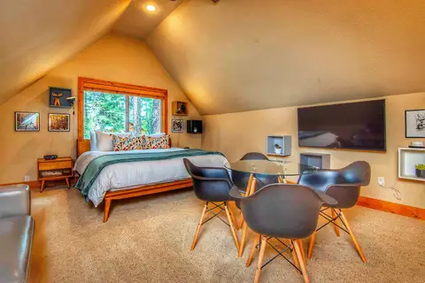 Loft bedroom with a bed, small dining table and wall TV, Restful North Ridge