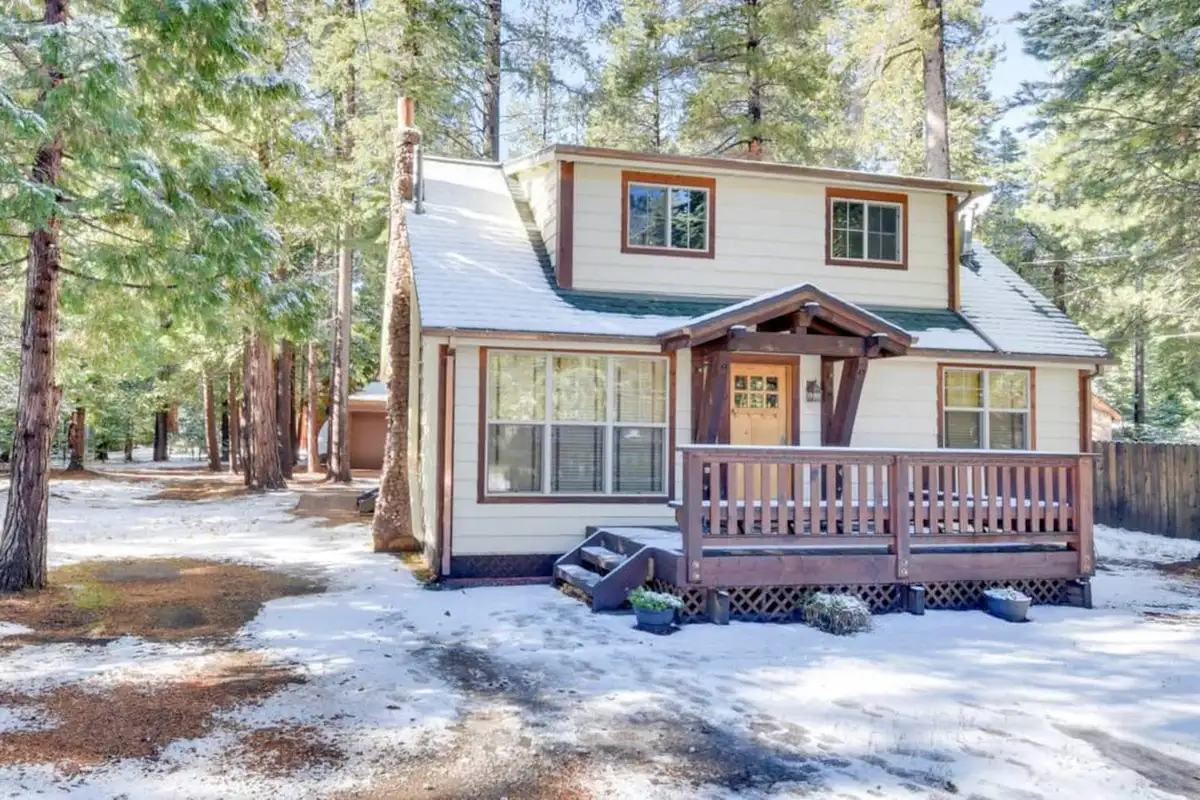 Two-story cabin with a front porch in light snow, Tranquil Trails Cabin