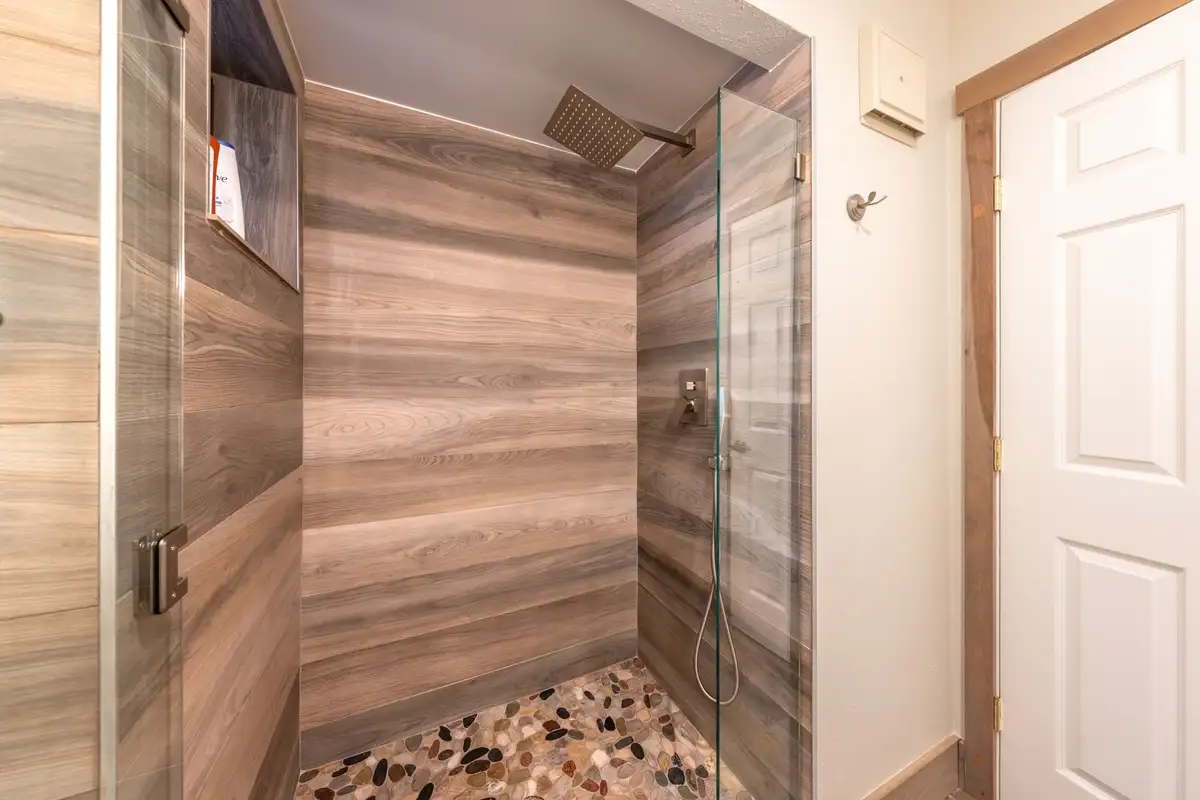 Walk-in shower with wood-look tile and pebble floor, Tranquil Stay