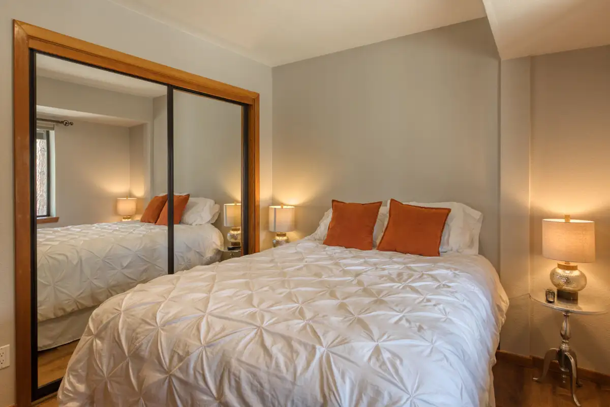 Bedroom with a white bed and mirrored closet doors, Lunar Lakeview Haven
