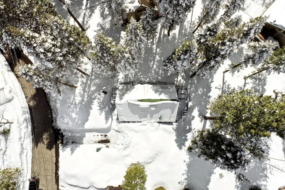 Aerial view looking down on a snowy roof and pines, Patton's Pfeiffer Cabin