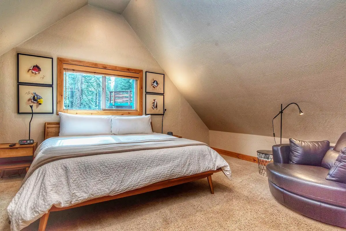Bedroom with a bed and round leather chair under sloped ceiling, Restful North Ridge