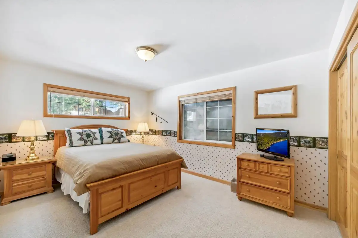 Bedroom with a wood bed and small TV, Hastings Hideaway Cabin